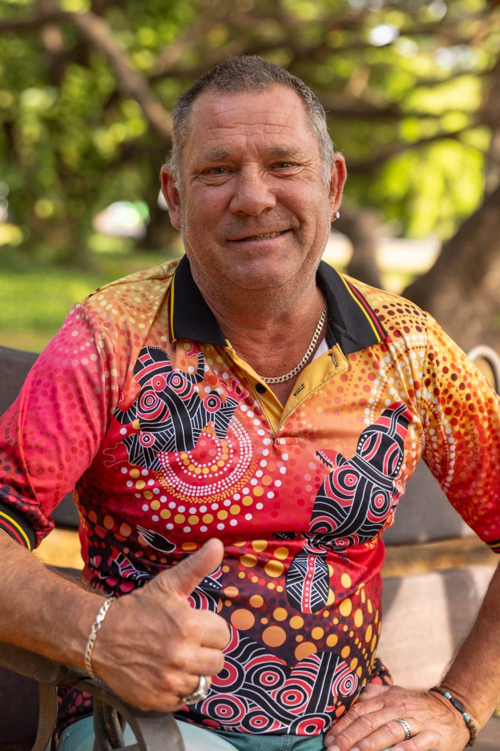 A smiling man giving a thumbs up outdoors
